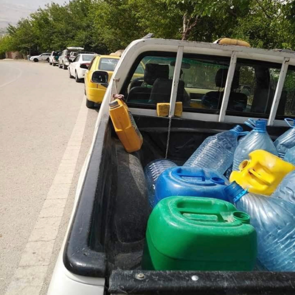The back of a pickup truck holding multiple jugs of water.