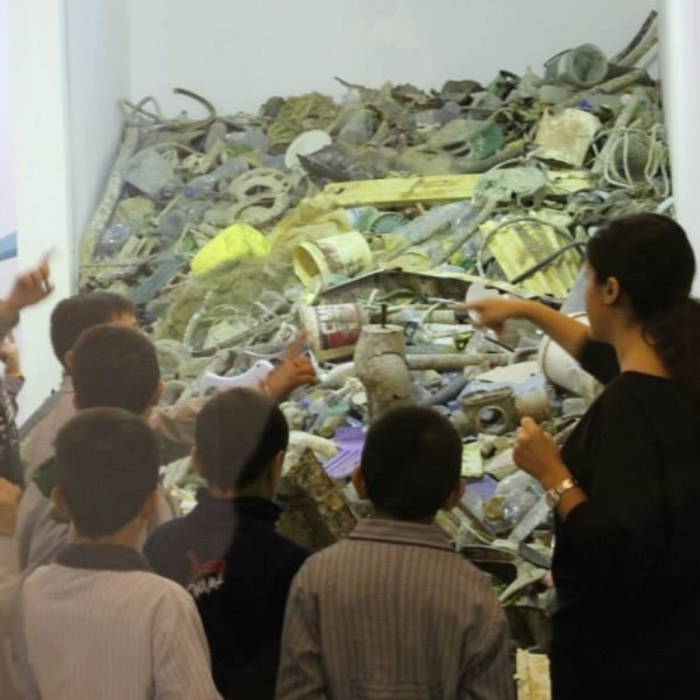 A woman showing a group of students an exhibit about plastic pollution.