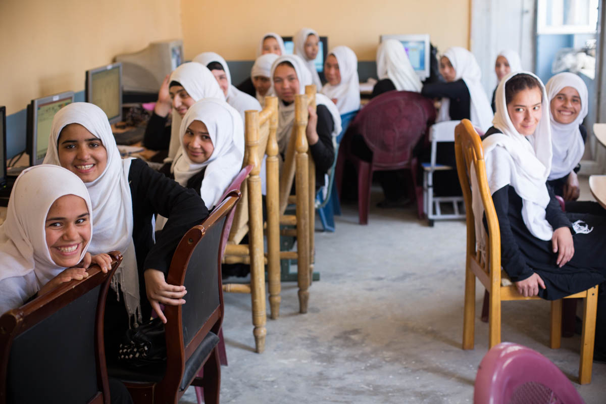 A group of young girls sitting on chairs at school and smiling