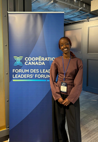 Laika standing beside a Cooperation Canada Leaders Forum pull up banner.